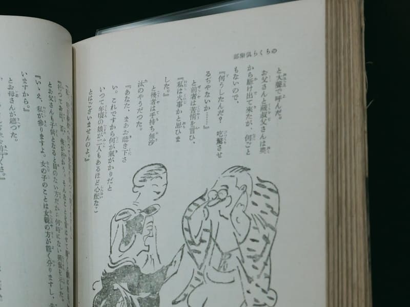 Open Japanese book with an ink illustration of two figures