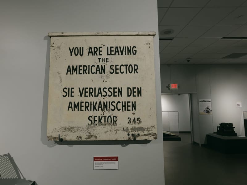 Weathered bilingual sign reading You Are Leaving The American Sector