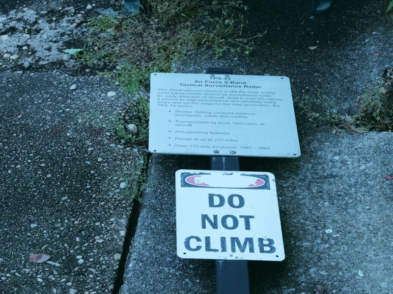 Site information placard beside a Do Not Climb warning sign