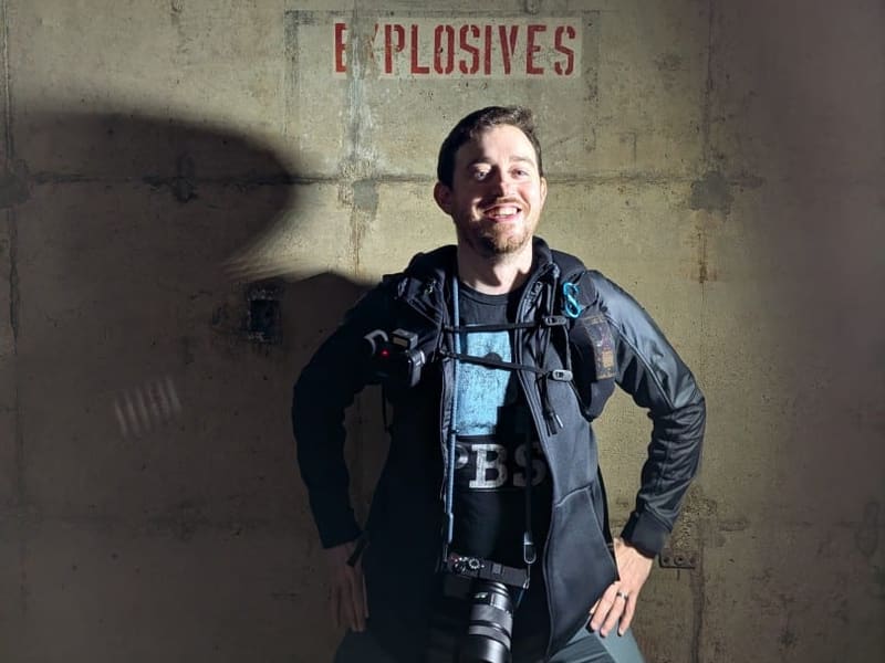 Brian Thackston posing beneath a stenciled Explosives wall marking