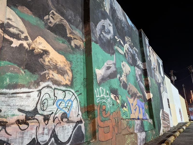 A large painted mural and graffiti on a wall at night