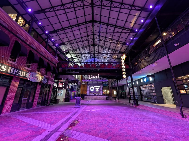 The empty Power Plant Live courtyard lit purple at night