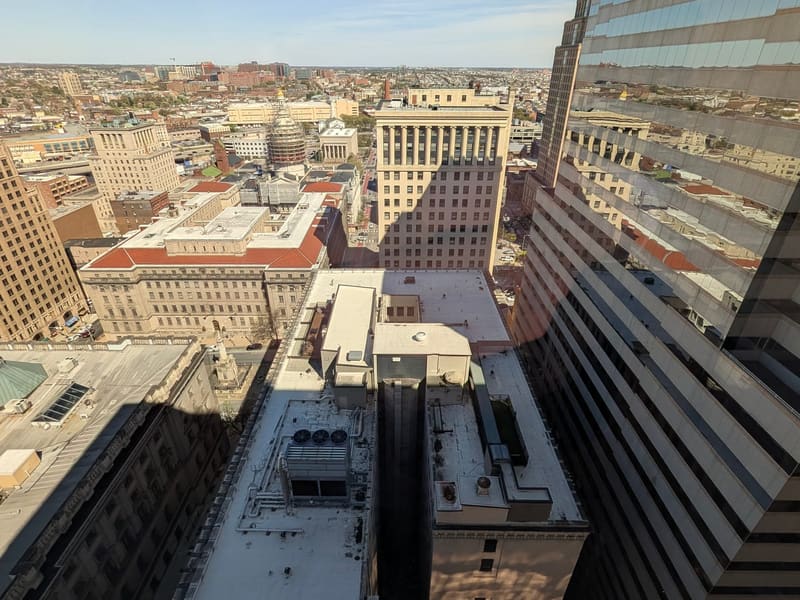 Sunlit aerial of downtown Baltimore beside a mirrored office tower