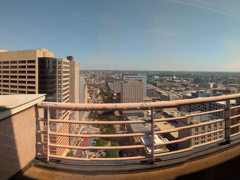 Panoramic rooftop-balcony view across the Baltimore skyline