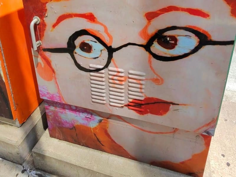 A utility box painted with a bespectacled face amid orange flames, Cleveland street art