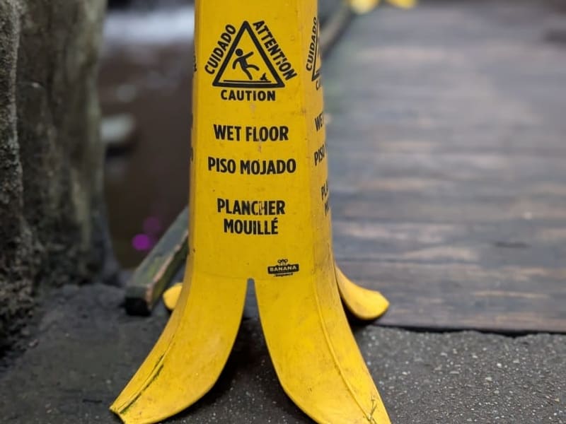 A wet-floor caution sign shaped like a banana peel on a garden path