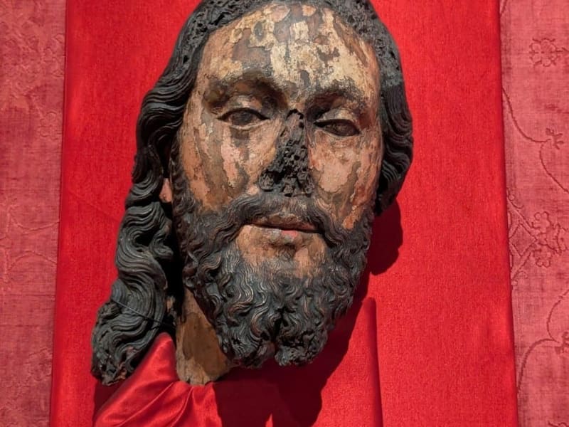 A weathered carved head of Christ mounted on red silk at the Gardner Museum