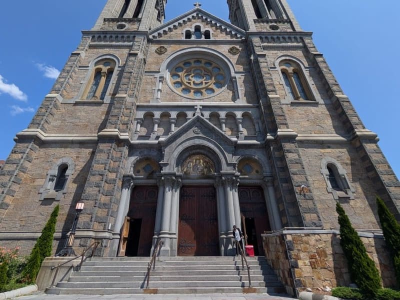 The twin granite towers and rose window of a Boston church seen from below