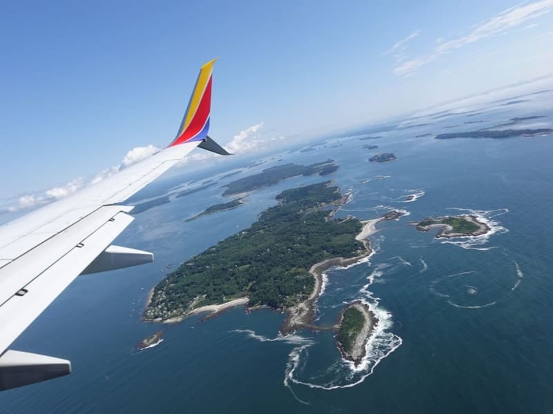 Aerial view of forested Maine islands and coastline from a plane window
