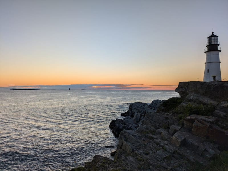 Portland Head Light on its rocky cliff at sunset over the water