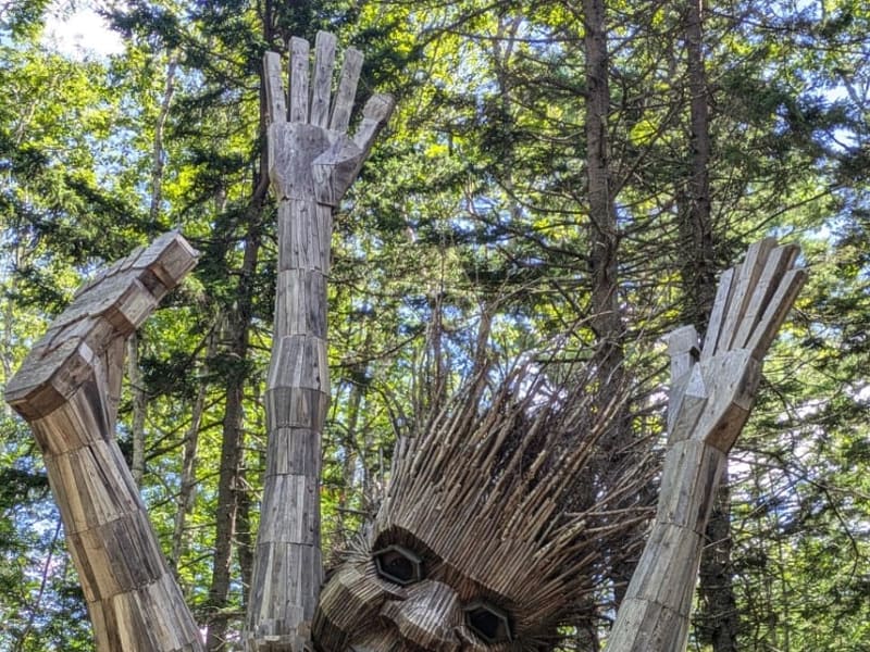 A giant reclaimed-wood troll sculpture in the woods at Coastal Maine Botanical Gardens