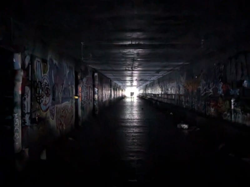 Light at the end of a dark graffiti-lined pedestrian tunnel