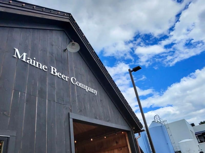 The black-clad tasting room of Maine Beer Company under a bright sky