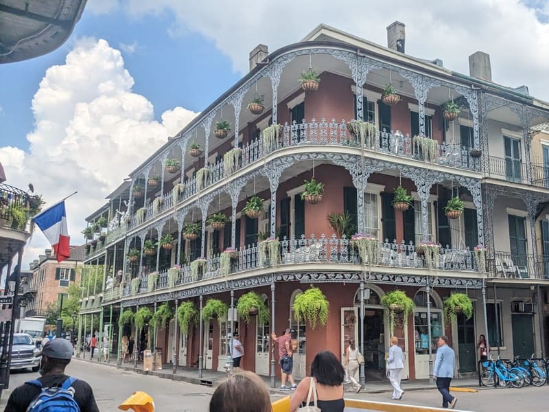 A classic French Quarter corner building with triple-tiered wrought-iron galleries draped in ferns, New Orleans