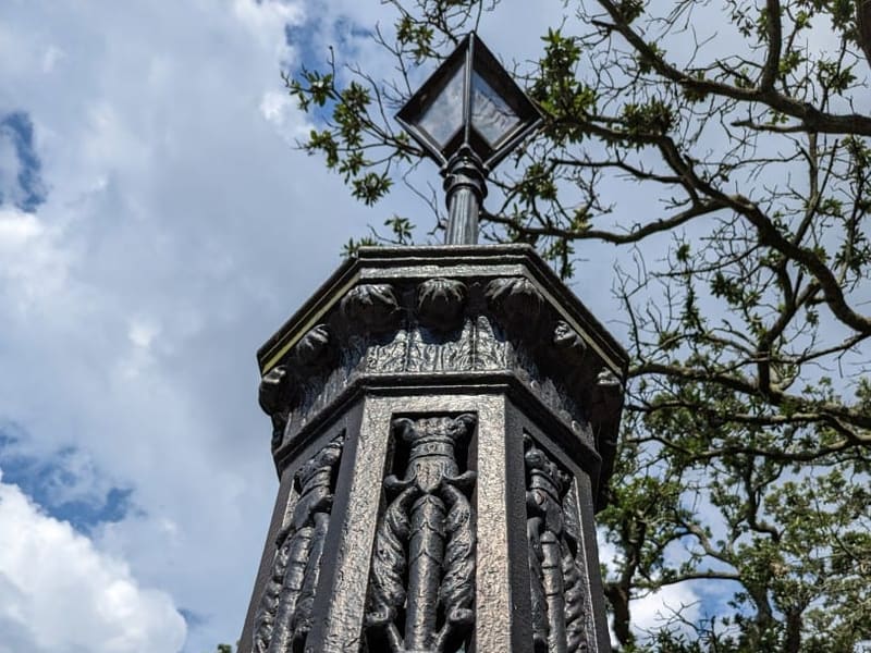 Ornate cast-iron fence post detail against a cloudy New Orleans sky