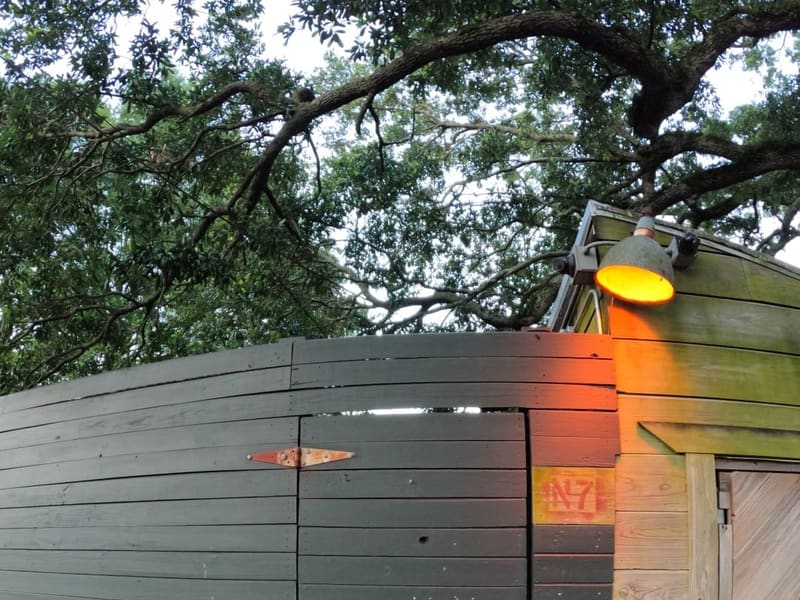 The green clapboard exterior of Dr. Bob's Bywater studio hung with painted folk art