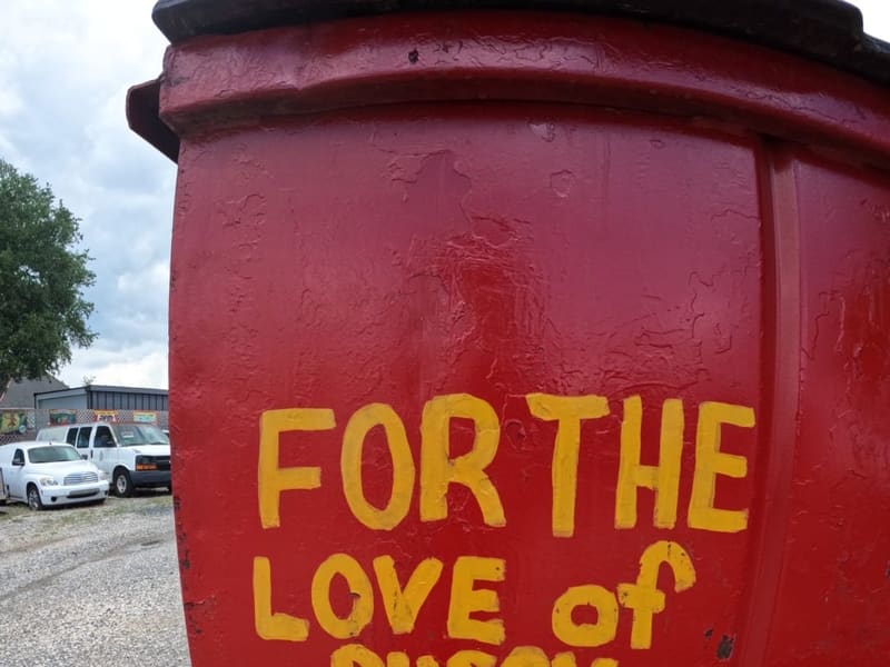 A red barrel hand-painted with a black cat and the words 'For the love of pussy, slow down'