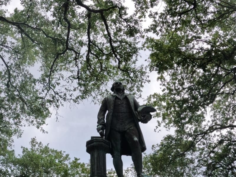 The bronze George Washington statue in New Orleans, framed by oak branches