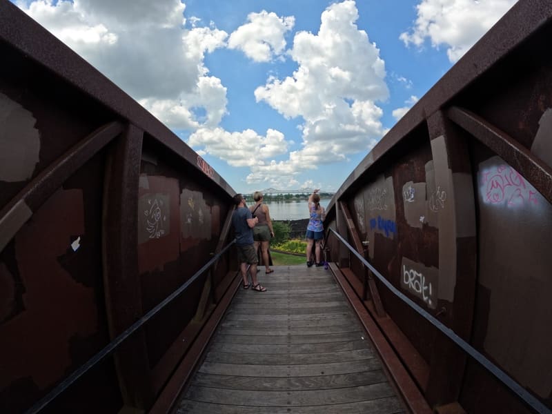 Visitors taking in the Mississippi River from a rusted steel overlook ramp