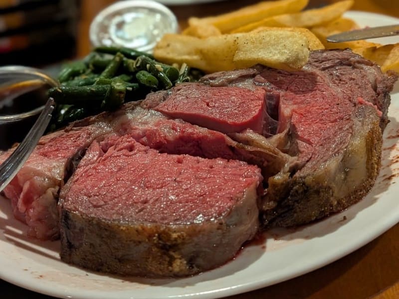 A thick slice of prime rib with fries and green beans at a Las Vegas steakhouse