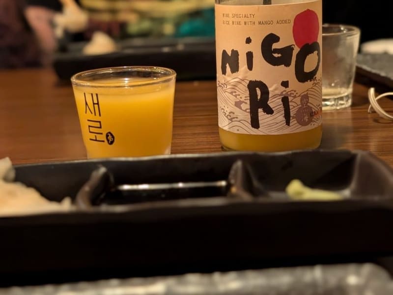 A bottle of Nigori mango rice wine poured at a sushi bar