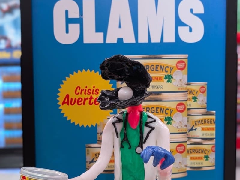 An 'Emergency Clams' satirical art display with a clay clam-doctor figure at Omega Mart