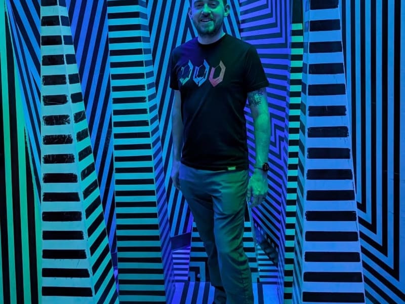 A visitor standing inside the black-and-blue op-art illusion room at Meow Wolf's Omega Mart