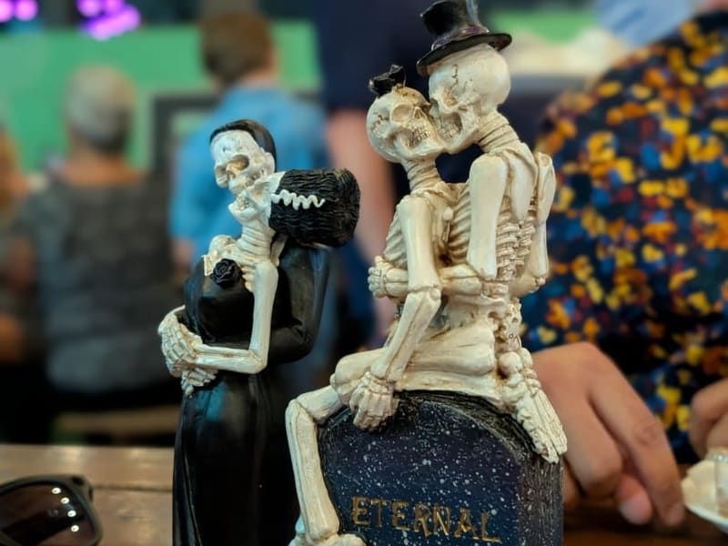 A gothic 'Eternal Love' souvenir of two skeleton couples perched on a tombstone
