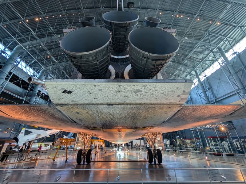 Space Shuttle Discovery seen from behind, its three main engines and tail filling the hangar
