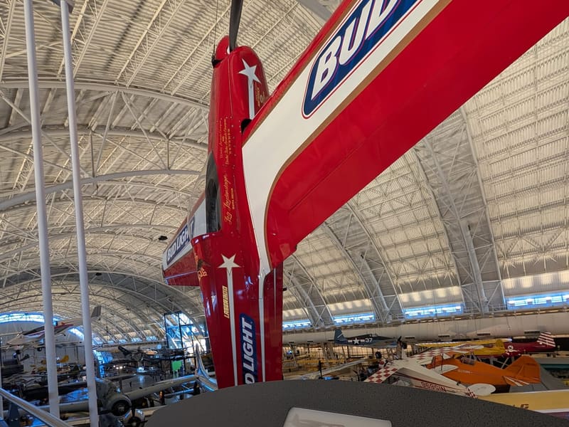 The red, white and blue Loudenslager Laser 200 aerobatic plane suspended above its placard