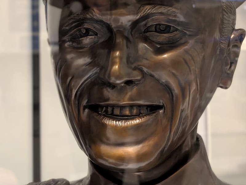 A bronze bust of a smiling U.S. Navy officer in dress cap