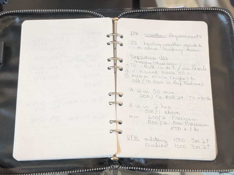 A pilot's open notebook with handwritten IFR weather-requirements notes