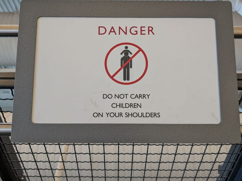 An observation-deck sign reading 'DANGER — Do not carry children on your shoulders'