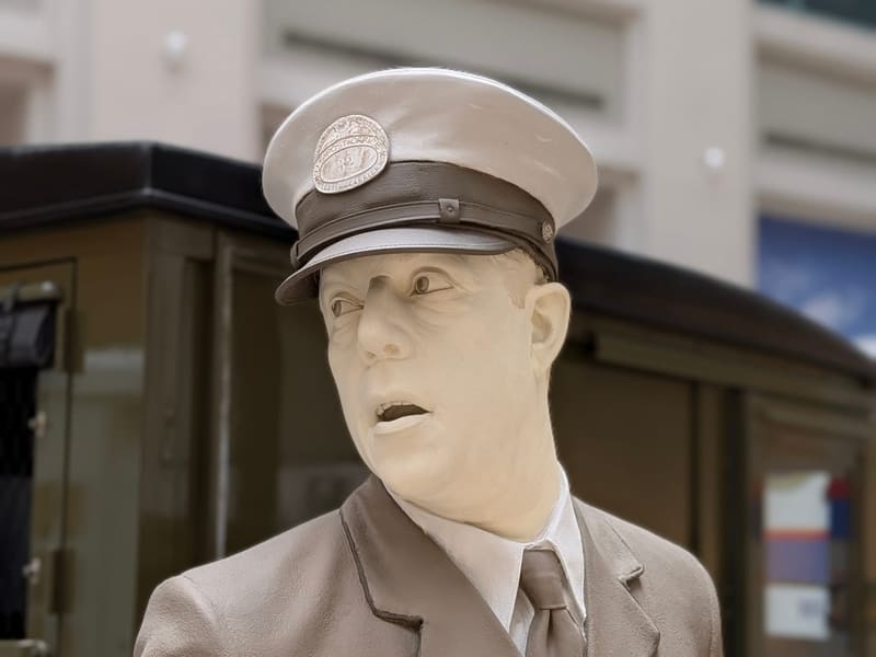 A lifelike figure of a uniformed letter carrier from an earlier era