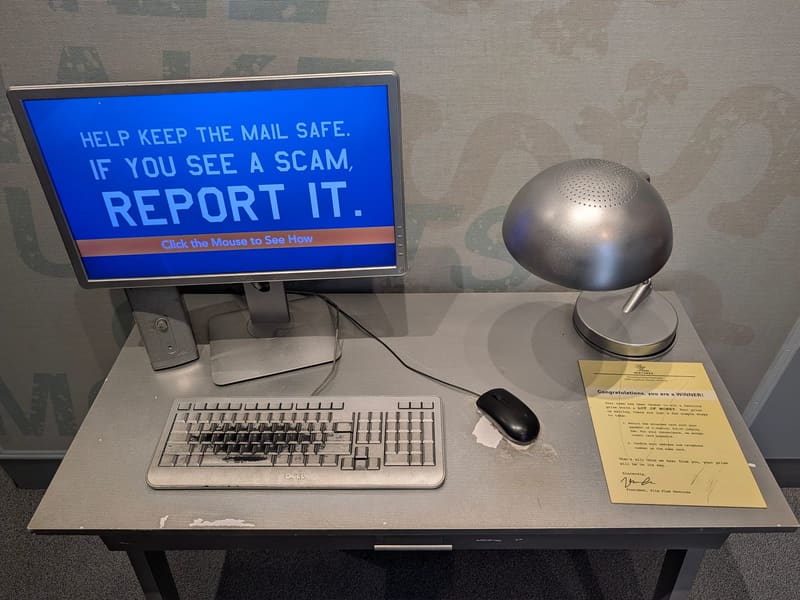 An interactive exhibit screen urging visitors to report mail scams