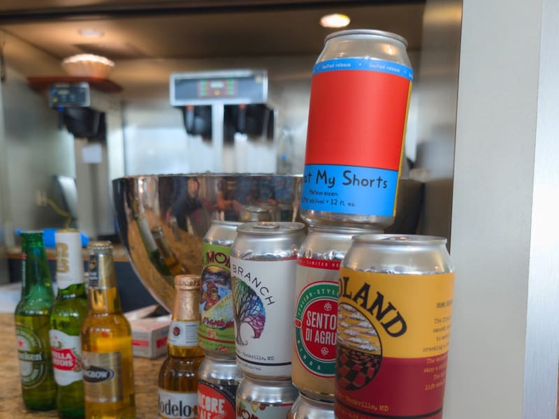 Bar counter lined with beer bottles and cans, including local Rockville, Maryland brewers alongside Heineken, Stella Artois and Modelo.